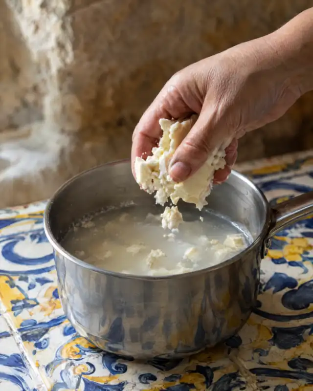 Sbriciolare la pasta di mandorle dolce in acqua tiepida in un pentolino