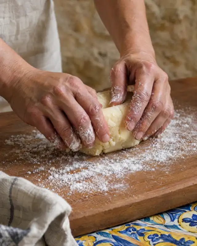 Lavorare la pasta di mandorle dolce raffreddata su una superficie spolverata con zucchero a velo