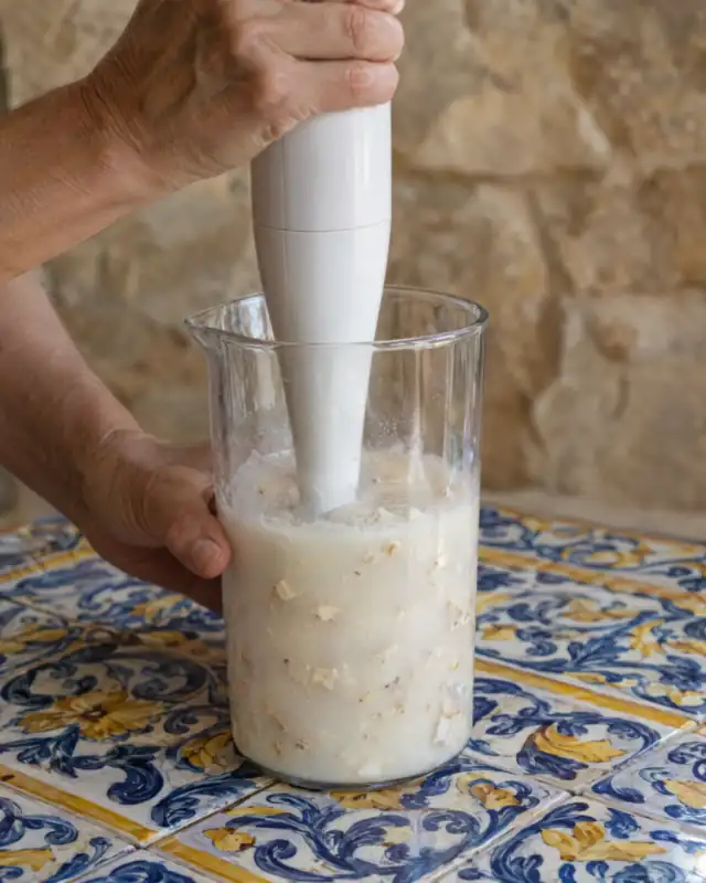 Frullare la pasta di mandorle dolce con acqua usando un frullatore a immersione