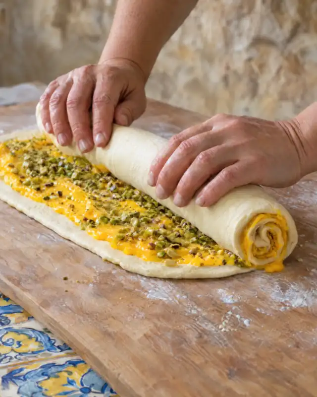 Arrotolare l'impasto con la crema all'arancia e i pistacchi tritati