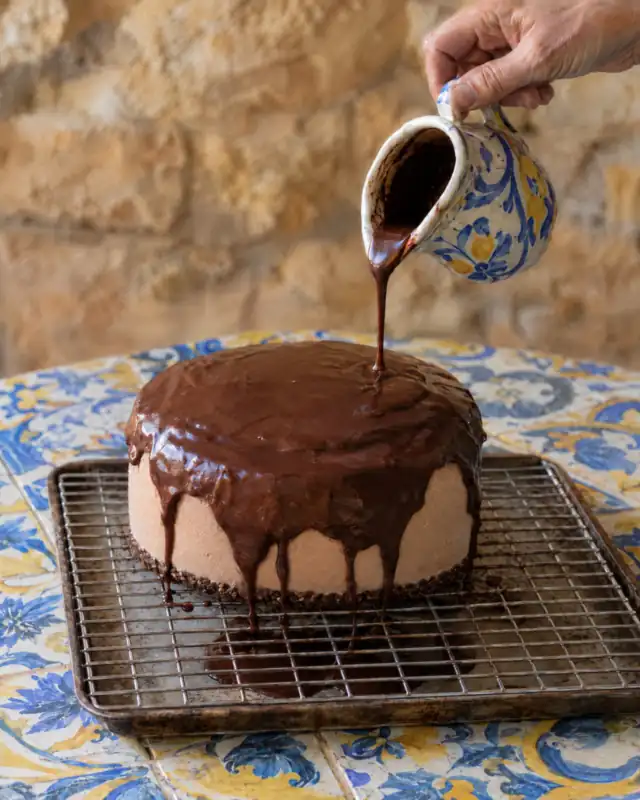 Versare la glassa a specchio al cioccolato sulla torta congelata posta su una gratella