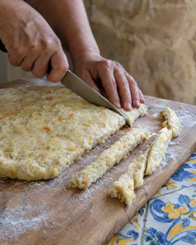Tagliare l'impasto di riso lievitato a strisce su una spianatoia infarinata